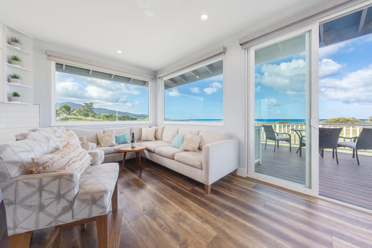 A corner living room with wide windows onto the ocean and a lanai