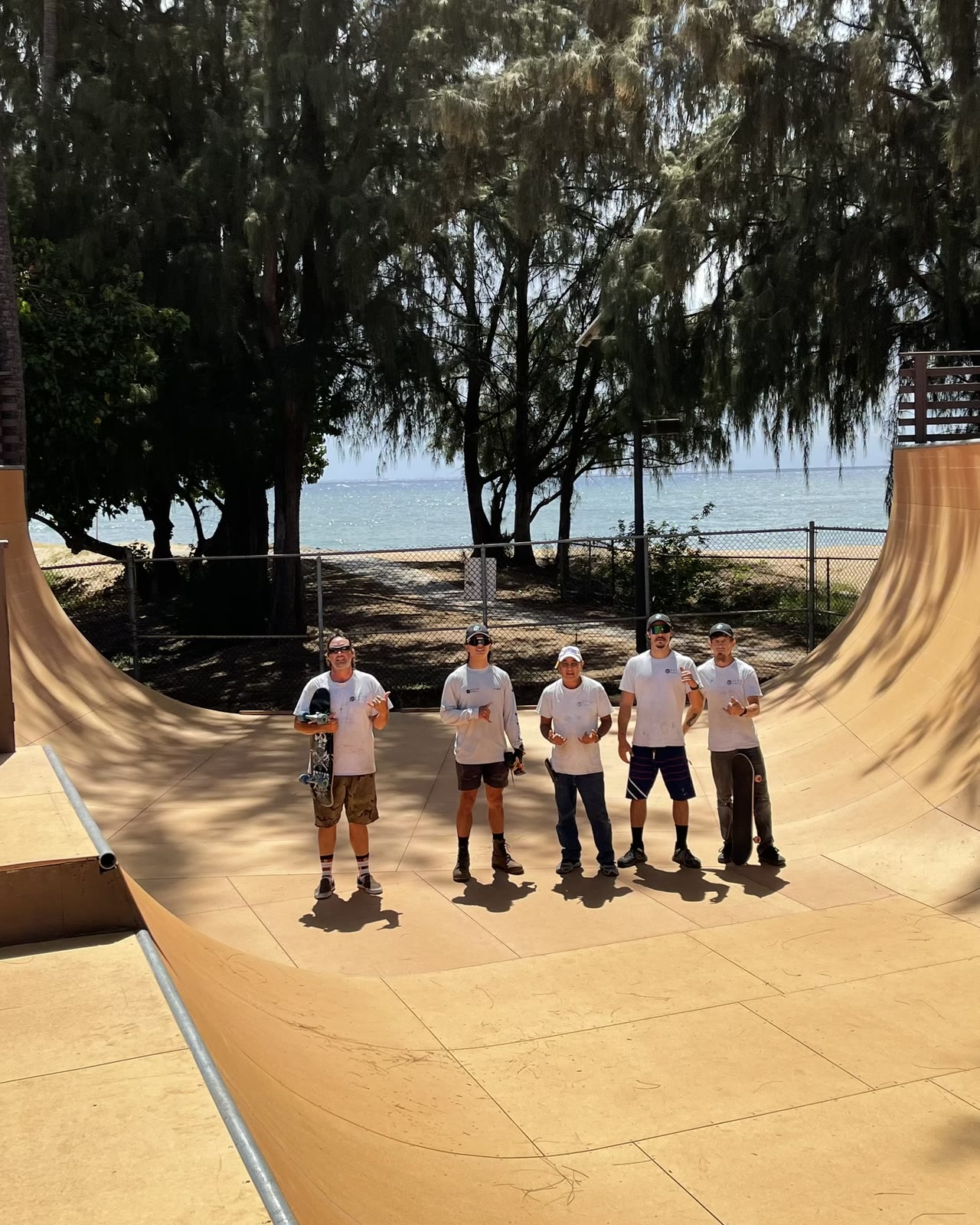 The Breen Builders crew standing together in a wooden skate ramp, with trees and the ocean behind them